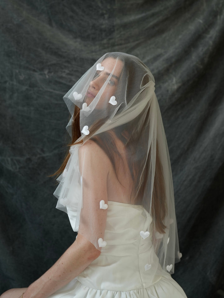 Woman wearing a mini bachelorette veil adorned with heart-shaped features