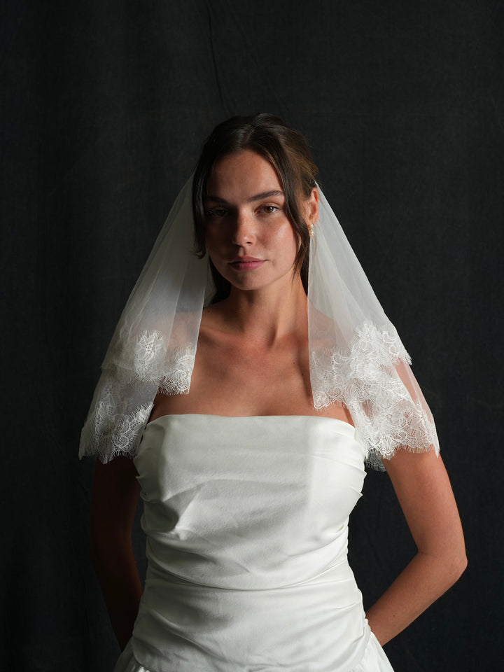 Woman wearing a white strapless dress and a chantilly lace short two tier bachelorette veil