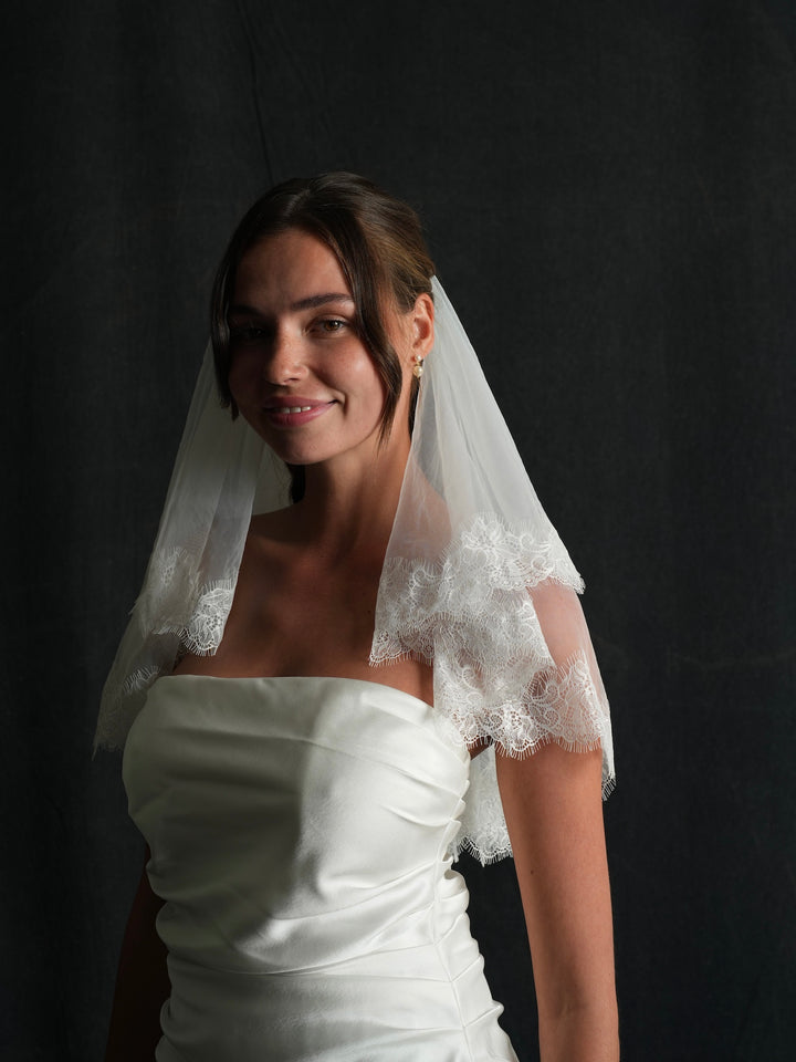 Woman wearing a white wedding dress with a mini lace short two tier bachelorette veil 