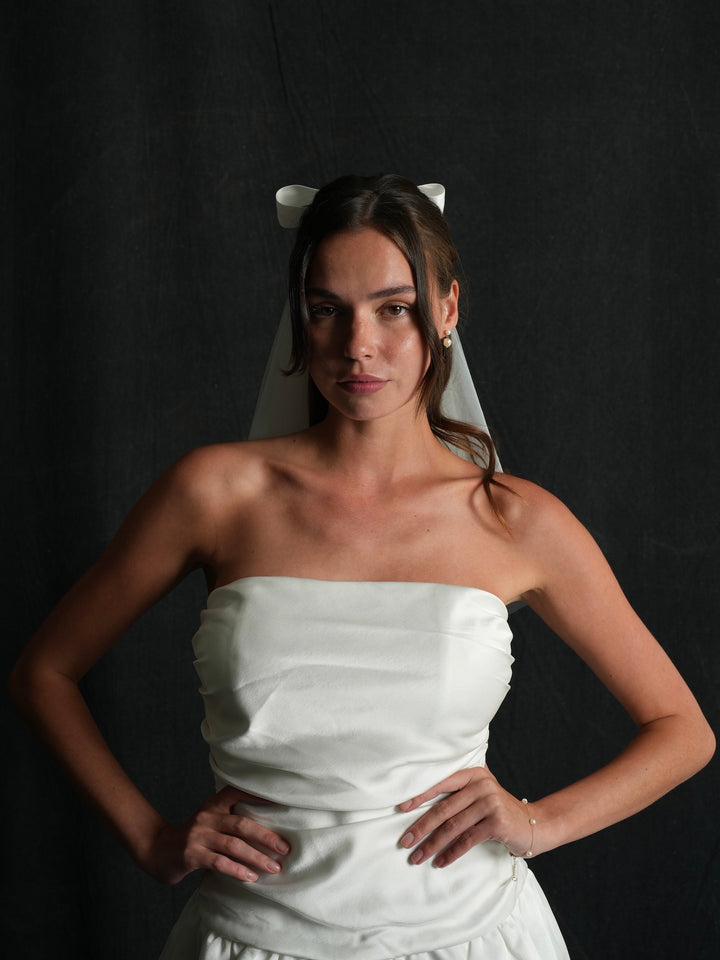 Woman in a strapless white dress wearing a mini bow short two tier bachelorette veil