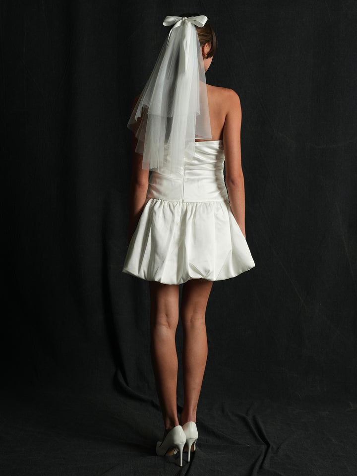Person wearing a white dress with a back profile of a mini bow short two tier bachelorette veil