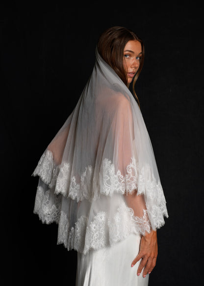 Woman wearing a two tier fingertip length lace veil, side profile