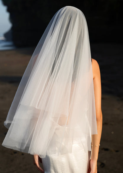 Person wearing a short simple plain classic veil, fingertip length, two tier back angle