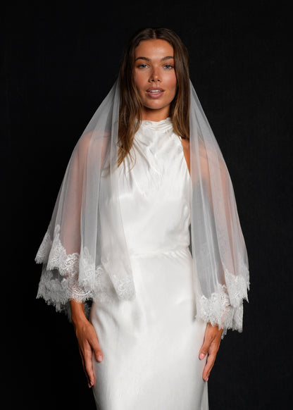 Front view of a woman wearing a chantilly short lace veil, two tier, fingertip length