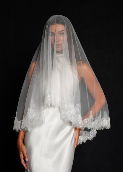 Bride wearing a white wedding dress with a chantilly short lace veil, two tier, fingertip length covering her face
