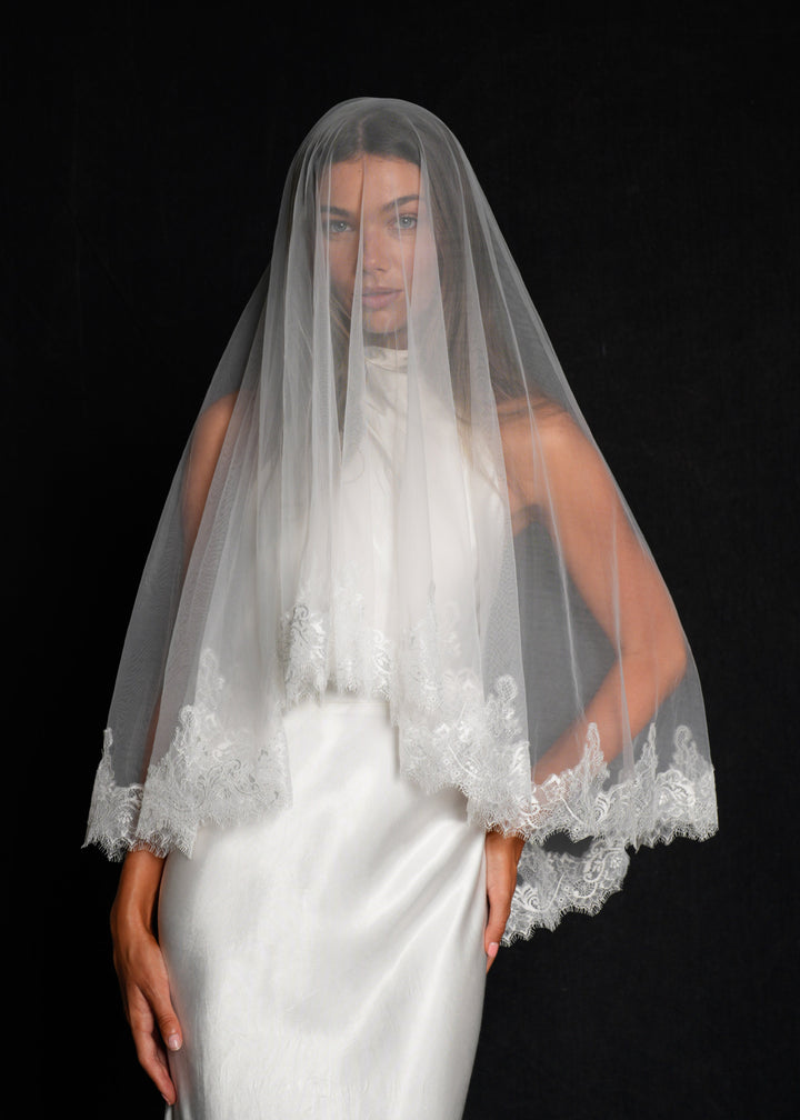 Bride wearing a white wedding dress with a chantilly short lace veil, two tier, fingertip length covering her face